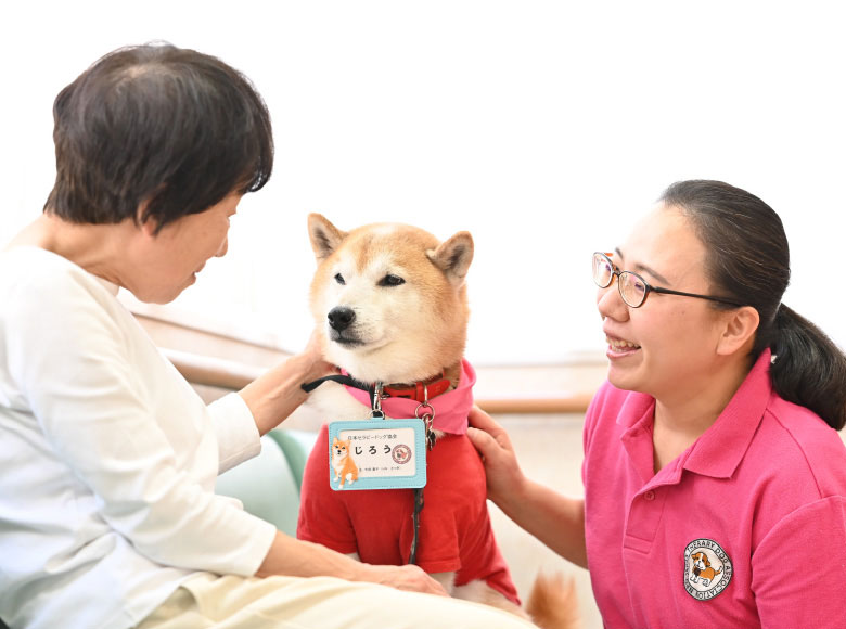 介護職員と入居者がセラピー犬とふれあう風景